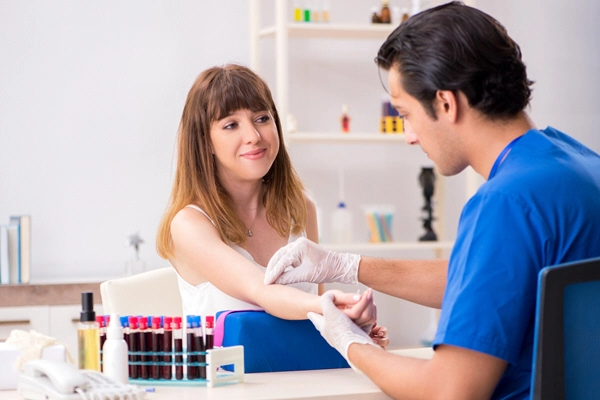 male doctor taking blood from female patient