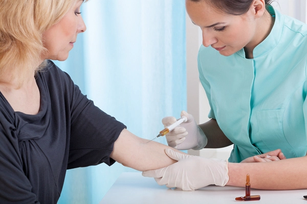 nurse giving injection to middle aged female patient in hospital room