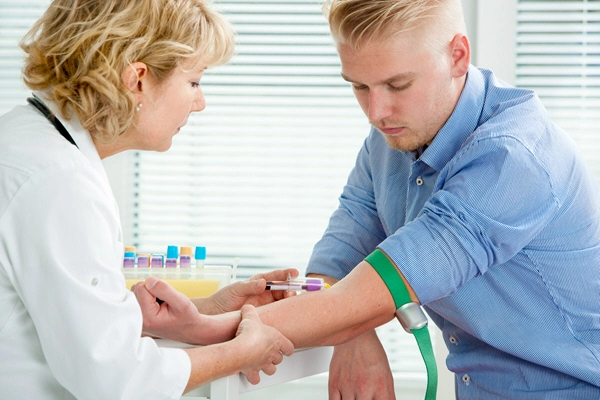 nurse taking blood sample from male patient at the doctors office