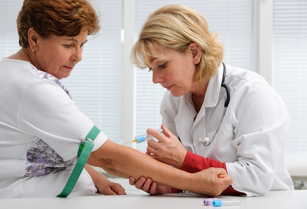 nurse with syringe is taking blood for test at the doctors office