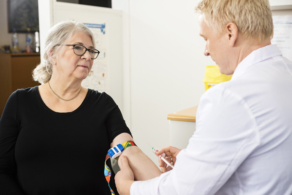 patient looking at male doctor collecting blood in syringe patient looking at male doctor collecting blood in syringe