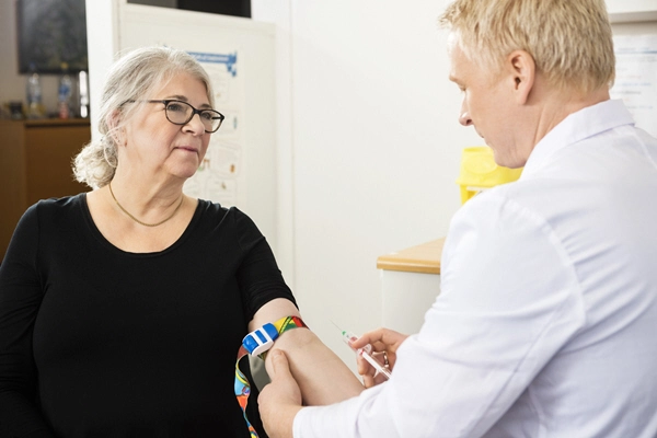 patient looking at male doctor collecting blood in syringe