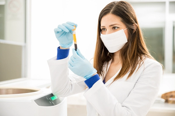 portrait of a beautiful hispanic chemist looking at a blood test tube out of a centrifuge in a laboratory