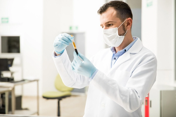 portrait of a handsome male chemist looking at a test tube with a blood sample in a laboratory