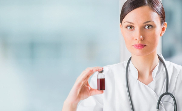 portrait of pretty female laboratory assistant analyzing a blood sample at hospital