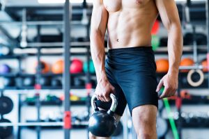 unrecognizable young fit man doing strength training exercising with kettlebell in mod SBI 305238209 300x200