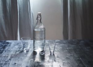 graphicstock glass of water with a bottle on wooden table_SdFxUYoDgog 300x214