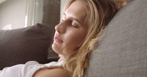 cute blond girl sleeping peacefully on a gray couch in soft daylight SBI 323255592 300x158