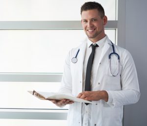 portrait of a male doctor holding his patient chart in bright modern hospital  300x257